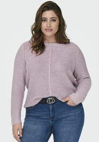 Kerge roosa kootud sviiter ümmarguse kaelusega, pika varrukaga ja soonikute äärtega. Kandub tumepruunide teksade peal, millel on must vöö metallist pandlaga.