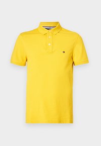 Polo jaune à manches courtes avec trois boutons et petit logo rectangulaire sur la poitrine gauche.