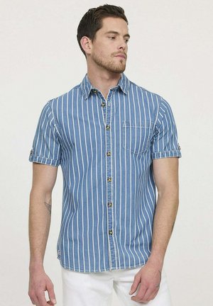 Chemise boutonnée à manches courtes en denim bleu clair avec rayures verticales blanches et une poche poitrine. Présente des boutons marron et des poignets retroussés.