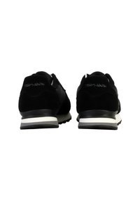 Zwarte suède sneakers met een witte tussenzool en een zwarte buitenzool. De achterkant heeft in het wit geperst tekst "TEDDY SMITH". Rond design van de teentip.