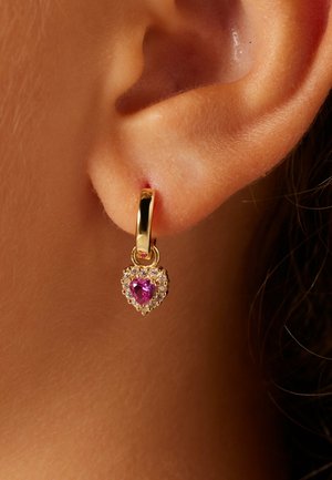 Boucle d'oreille en forme de cœur en or, ornée d'une pierre rose centrale entourée de petites pierres claires, attachée par un fermoir simple à anneau.