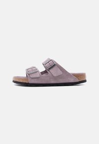 Ανοιχτό μωβ σουέντ σανδάλι Birkenstock με δύο ρυθμιζόμενα λουράκια με πόρπες και φελλό σόλα, εμφανίζεται από το πλάι σε λευκό φόντο.