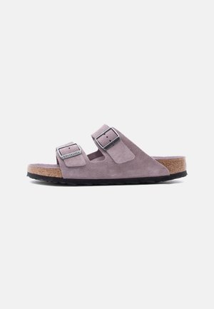 Ανοιχτό μωβ σουέντ σανδάλι Birkenstock με δύο ρυθμιζόμενα λουράκια με πόρπες και φελλό σόλα, εμφανίζεται από το πλάι σε λευκό φόντο.