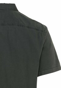 Camicia a maniche corte in tessuto grigio scuro, caratterizzata da un colletto classico, una texture liscia, cuciture visibili lungo la spalla e un design semplice.