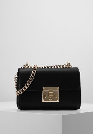 Sac à main en cuir noir avec un fermoir doré, une chaîne en bandoulière, une forme structurée, une texture lisse et un détail rectangulaire à l'avant.