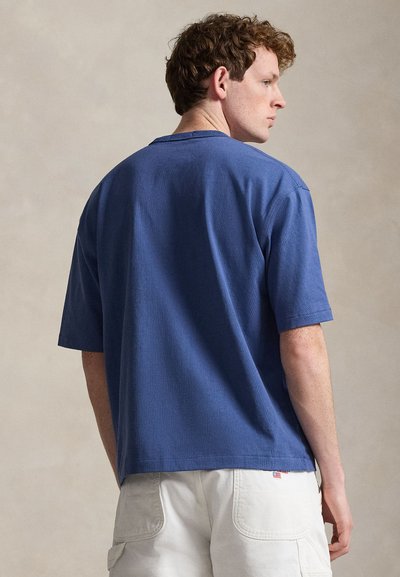 Μπλε κοντομάνικη μπλούζα με στρογγυλή λαιμόκοψη, ομαλή υφή και χαλαρή εφαρμογή. Χωρίς εμφανή λογότυπα ή σχέδια. Καθημερινή και πολυχρηστική σχεδίαση.