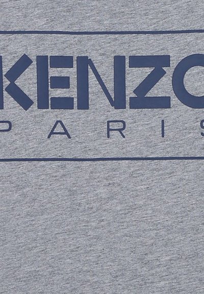 T-shirt gris avec le logo "KENZO" en bleu marine audacieux et le texte "PARIS" en dessous, avec une texture douce et chinée. Design simple et minimaliste.