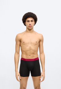 Μαύρα boxer briefs με αντίθετη κόκκινη μέση που φέρει το κείμενο "TOMMY HILFIGER". Λείο ύφασμα, εφαρμοστή σχεδίαση και μήκος έως τη μέση του μηρού.