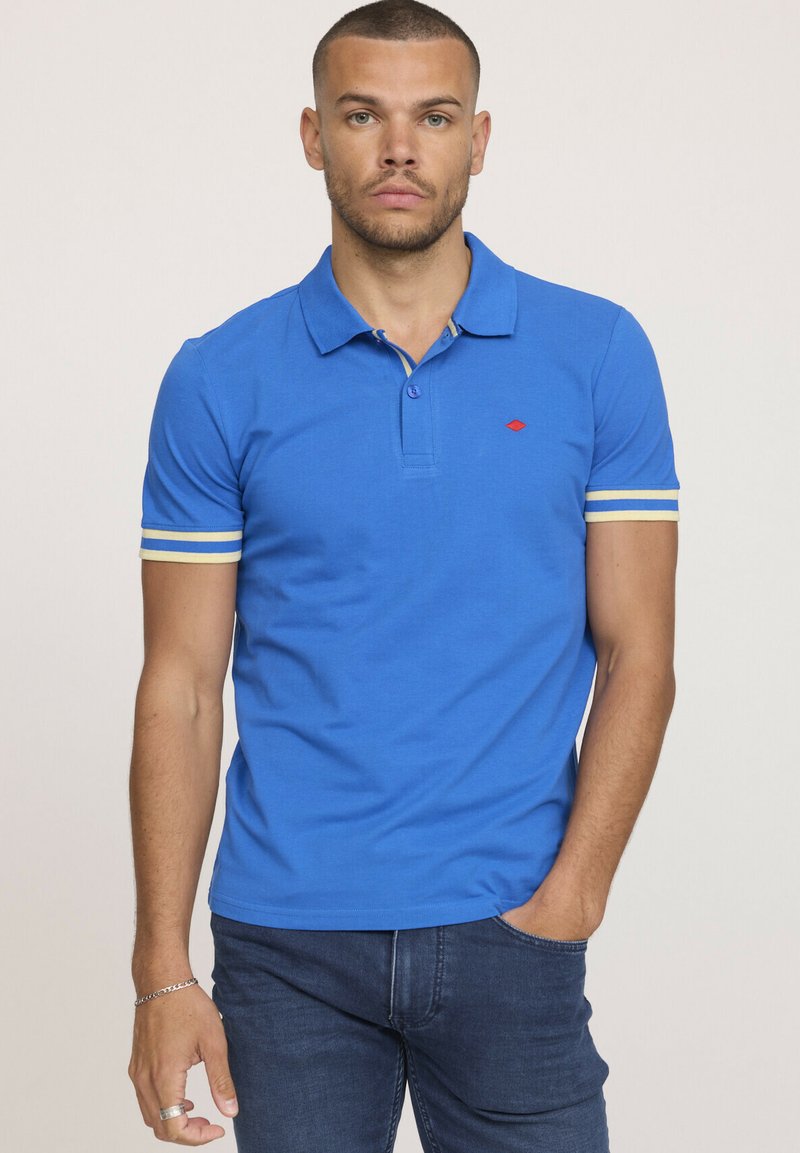 Polo shirt bleu en coton avec un design col, présentant des rayures jaunes contrastantes sur les manches et un petit logo rouge sur la poitrine.