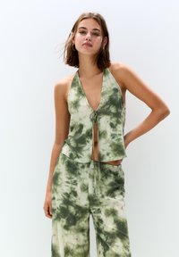 Grön och beige tie-dye halterneck-topp med djup V-ringning och knutdetalj framtill; avslappnad passform, lätt tyg, slät textur.