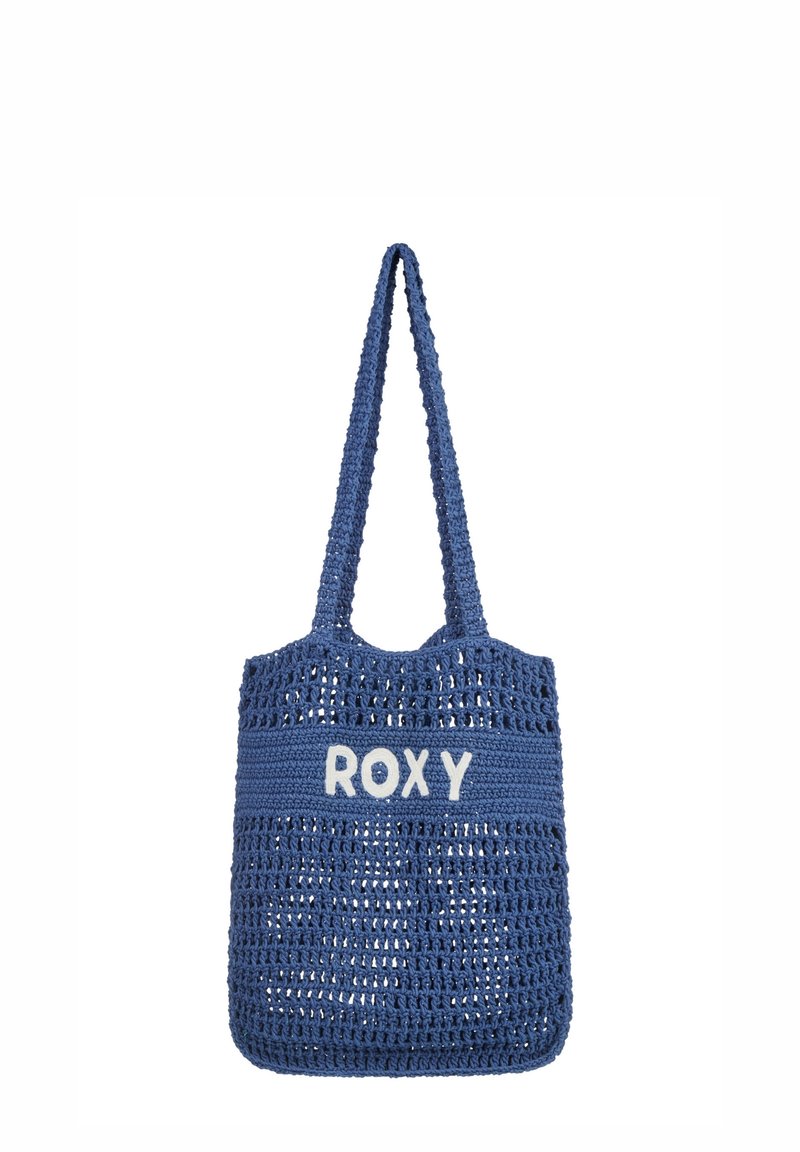 Borsa a mano all'uncinetto blu con una forma ampia e piatta e due manici. Presenta la scritta "ROXY" in bianco, con lettere spesse su una fascia solida. Materiale testurizzato.