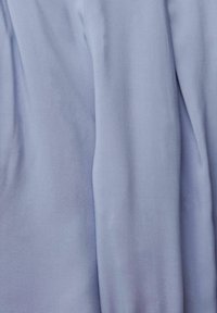 Jasnoniebieska tkanina o gładkiej fakturze i miękkim układzie, z delikatnymi zagięciami i zagnieceniami nadającymi swobodny wygląd.