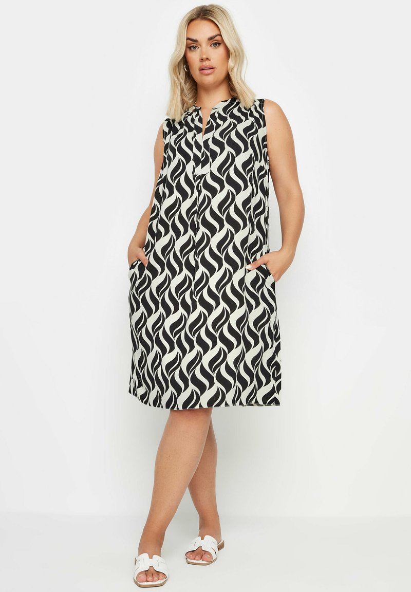 Mustaton ja valkoinen aalto-kuvioinen hihaton mekko, jossa on napitus edessä, sivutaskut ja löysä istuvuus, valmistettu kevyestä kankaasta.