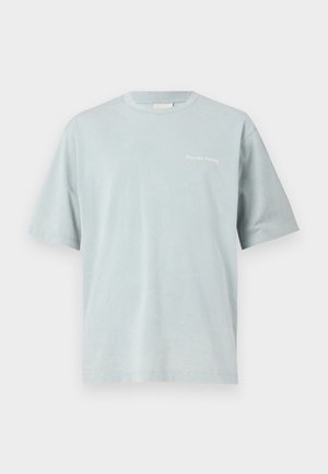 T-shirt azzurro chiaro a maniche corte con scollo tondo e la scritta "Filling Pieces" in piccolo bianco sul petto sinistro.