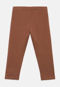 Καφέ ελαστικό ύφασμα κολάν με απλή ελαστική μέση και χωρίς ορατά σχέδια ή λογότυπα, απλωμένα επίπεδα σε λευκό φόντο.