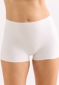 Weiße Baumwoll-Boyshorts mit nahtlosem Design und glatter Textur. Der Bund sitzt direkt über den Hüften und bietet vollständige Abdeckung.