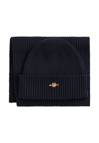 Marineblauw gebreide muts en sjaal set, met een geribbelde structuur en een omgevouwen ontwerp, met een klein geborduurd logo op de muts.