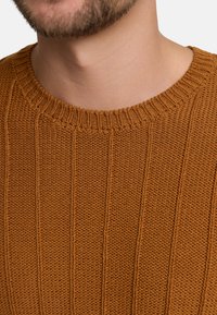 Brown knitted sweater featuring vertical ribbing, a round neckline, and a textured weave, showcasing a soft and cozy appearance.