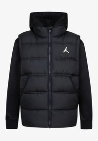Gilet en duvet noir avec capuche, fermeture éclair et poches latérales. Il présente une texture douce et un logo Jumpman blanc sur la poitrine.