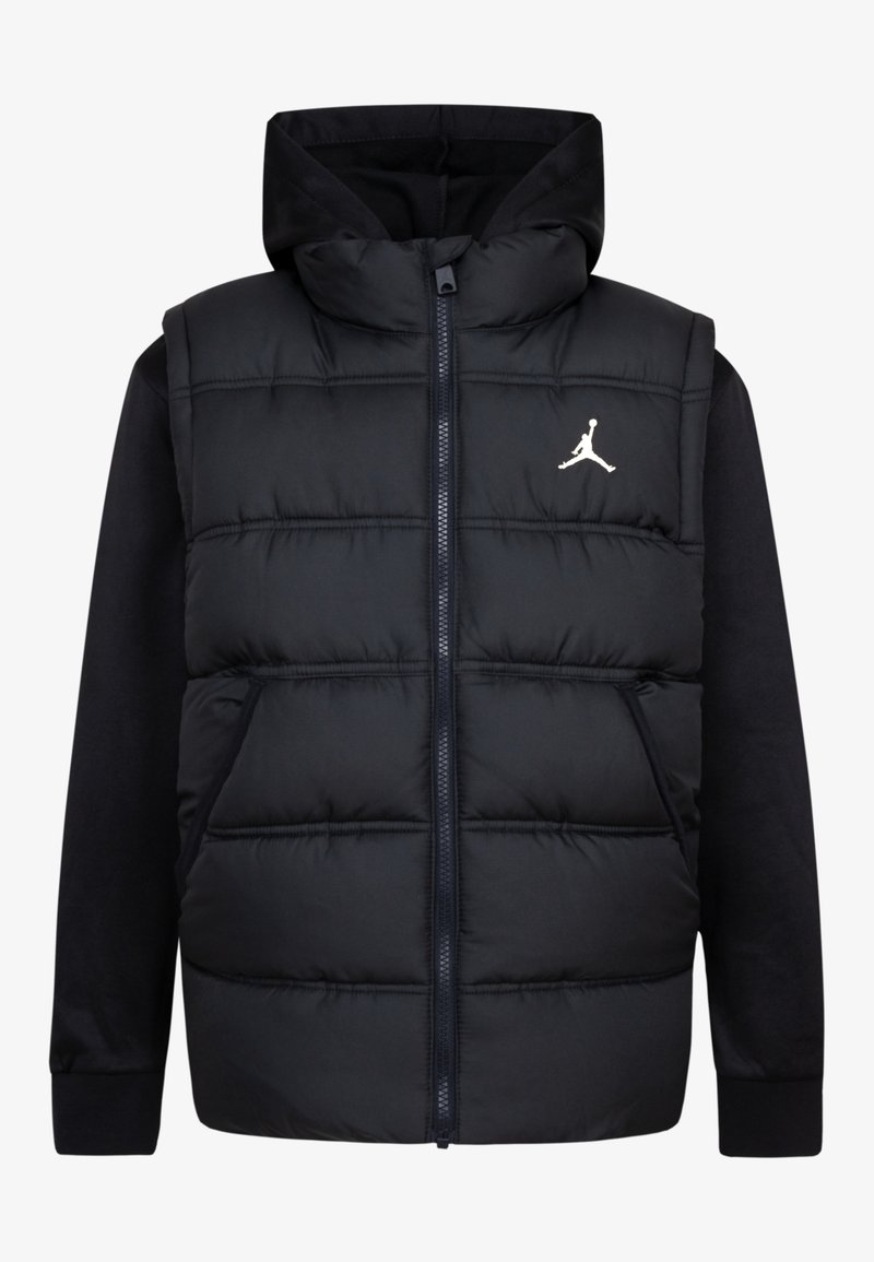 Gilet en duvet noir avec capuche, fermeture éclair et poches latérales. Il présente une texture douce et un logo Jumpman blanc sur la poitrine.