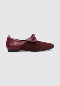 Zapato plano burdeos con punta redondeada, que presenta un gran lazo decorativo y una combinación de texturas de cuero suave y gamuza.
