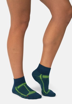 Blaue und grüne Sportsocken mit geripptem Bündchen, strukturiertem Stoff und verstärkter Ferse. Verfügt über kontrastierende Streifen und gepolsterte Bereiche für zusätzlichen Komfort.