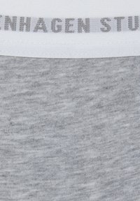 Šedá pruhovaná tkanina s textúrovaným povrchom, ktorá má biely elastický pás s potlačou "COPENHAGEN STUDIOS" v šedých písmenách.