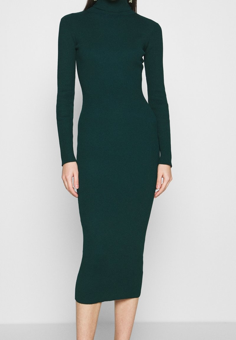 Robe col roulé en maille côtelée vert foncé, ajustée, manches longues, longueur mi-mollet, texture lisse avec un léger stretch.