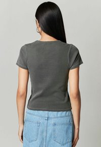 Grå bomulds t-shirt med korte ærmer og en tætsiddende pasform, der har en simpel rund halsudskæring og kontrastsyning detaljer.