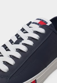 Tumesinised spordijalatsid valgete paelte ja tallaga, millel on Tommy Jeans logo plaaster keelel ja külgedel.