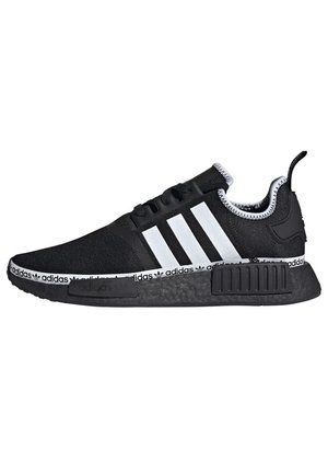 Baskets noires Adidas avec trois bandes blanches, semelle noire et bande blanche avec logo Adidas répété autour de la semelle intermédiaire.