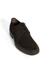 Chaussure de ville pour homme en cuir suédé marron foncé, à lacets, avec une épaisse semelle noire, présentée en angle sur fond blanc.