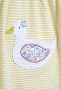 Un tissu à rayures jaunes présente un canard blanc brodé avec un accent floral et un motif floral coloré sur son corps.