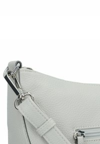 Borsa a mano in pelle grigia chiara con texture a ciottoli, dotata di zip argentata, tracolla regolabile e attacco ad uncino sul lato.