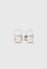 Silverfärgade sandaler med blockklack, öppen bak och tunn ankelrem. Blanka metallisk yta med en slät textur.