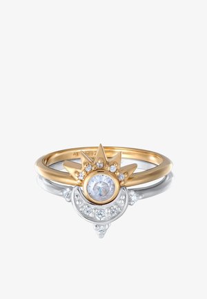 Złote i srebrne pierścienie z centralnym przezroczystym kamieniem, ozdobione mniejszymi kamieniami i projektowaniem w stylu korony z ostrymi akcentami.