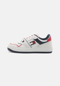 Zapatilla blanca de piel con acentos en azul marino y rojo, que cuenta con una suela de goma, puntera perforada y un logo de Tommy Jeans en el lateral.