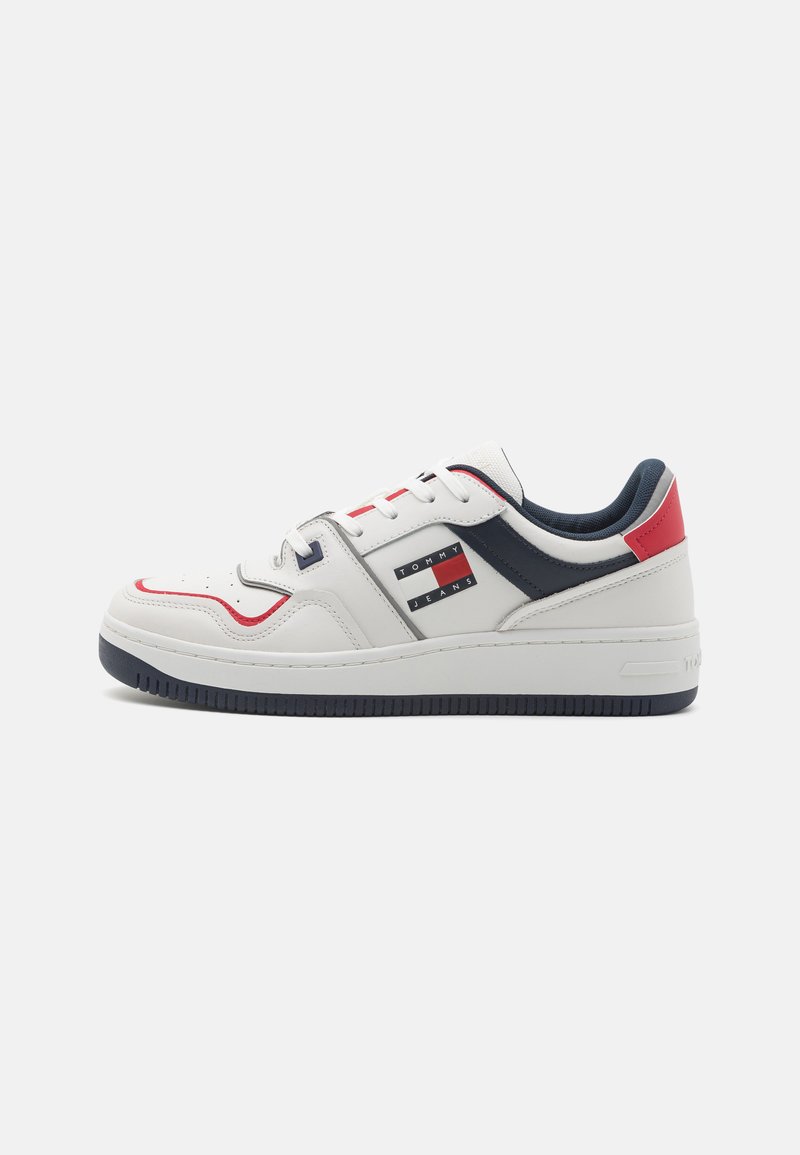 Zapatilla blanca de piel con acentos en azul marino y rojo, que cuenta con una suela de goma, puntera perforada y un logo de Tommy Jeans en el lateral.
