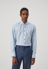 Lichtblauwe geblokte button-up shirt met een spreidkraag en donkere knopen, gecombineerd met donkerblauwe op maat gemaakte broeken. Glad fabric.