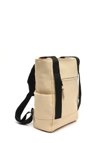 Zaino in finta pelle beige con spallacci neri regolabili, tasca frontale con zip, tasca laterale, forma rettangolare, superficie liscia.