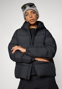 Doudoune noire avec capuche, dotée d'un zip à l'avant, de poignets côtelés et d'un design cropped. Matériau lisse et léger ; adaptée aux temps froids.