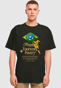 Sort t-shirt med et livligt gult og grønt brasilianisk fodboldgrafik med teksten "Brazilian Footwork Poetry" og en spiller i aktion.