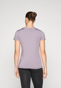 Short-sleeve athletic shirt in light lavender, featuring a fitted design, smooth texture, and a round neck, paired with black leggings.