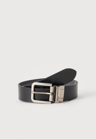 Ceinture en cuir noir avec boucle rectangulaire argentée et "Karl Lagerfeld Jeans" gravé sur la boucle métallique, enroulée sur un fond uni.