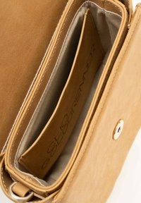 Tan leren tas met een gladde textuur, voorzien van een enkele compartiment, kaartslote en een gouden knoopsluiting. Interieur is gevoerd met neutrale stof.