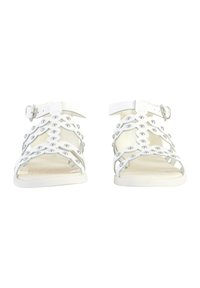 Sandalo bianco con design aperto, caratterizzato da cinturini intrecciati e dettagli circolari in argento. Cinturino alla caviglia regolabile e suola piatta.