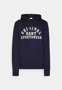 Sweat à capuche bleu marine avec poche avant, capuche à cordon et texte blanc indiquant "ORIGINAL GANT SPORTSWEAR" en lettres majuscules épaisses.