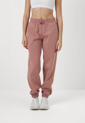 Helle rosa Baumwoll-Jogginghosen mit elastischem Bund und Bündchen. Mit einem Kordelzug-Detail und einem entspannten Schnitt. Kombiniert mit weißen Sneakern.