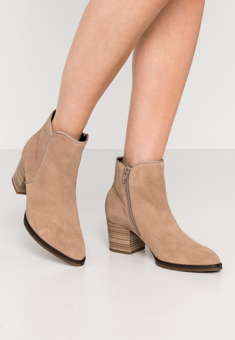 Beżowe zamszowe botki za kostkę z ostrym noskiem i bocznym zamkiem, z teksturowanym, warstwowym obcasem dla lepszej stabilności.
