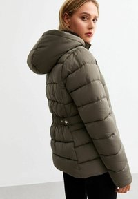 Chaqueta acolchada de color verde oliva con capucha, con diseño acolchado, cintura con cinturón y puños acanalados. Textura suave y ligero brillo.